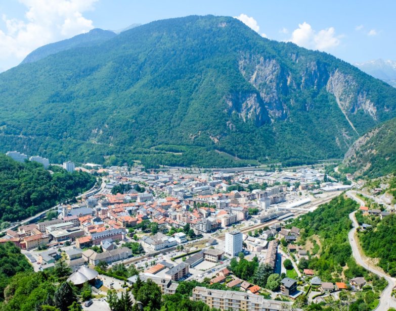 Vue aérienne de Moûtiers dans sa vallée, entourée de montagnes boisées